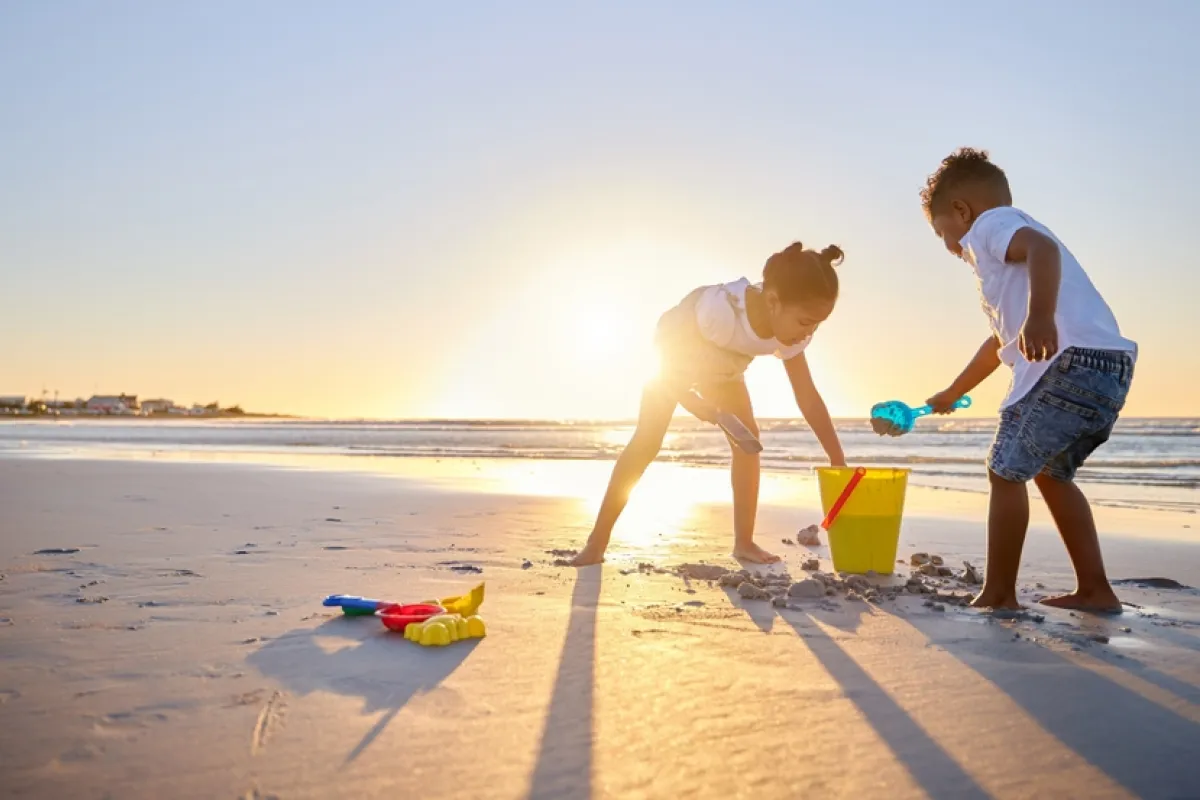 twee kinderen spelen op het strand bij zonsondergang